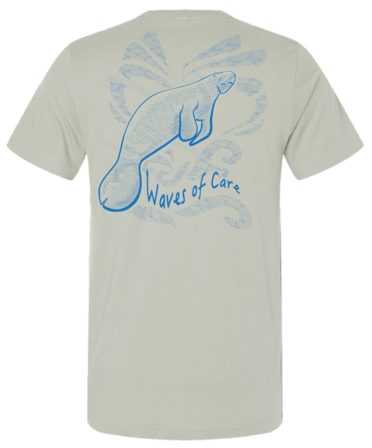 Light “thyme” colored T-shirt with a large blue manatee and wave illustration printed across the back.